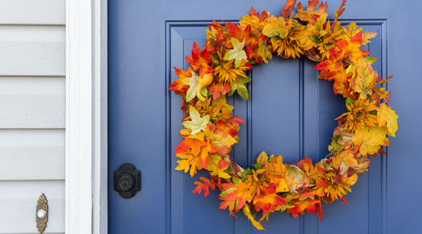 A blue door with a colorful wreath of autumn leaves