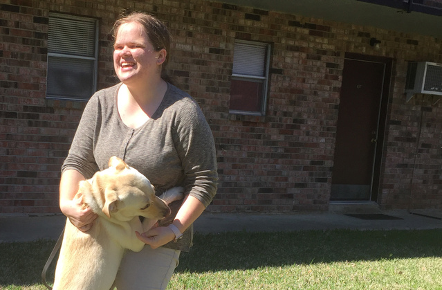 Aleeha Dudley's service dog Whitley jumps up on her outside their apartment in Louisiana