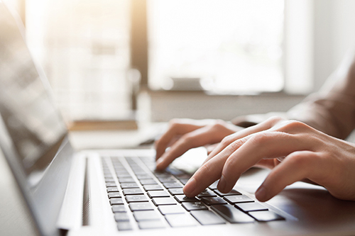 Hands typing on laptop keyboard