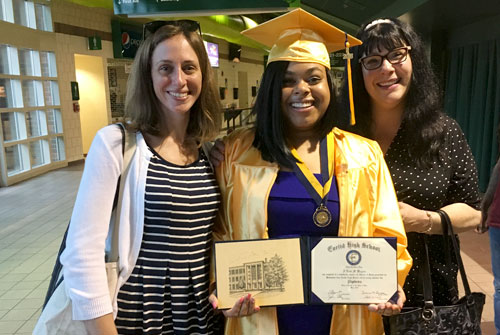 DRO attorneys Laura Osseck and Kristin Hildebrant pose with client Aloni Wagner as she wears her cap and gown and holds her diploma at her high school graduation