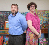 DRO Attorney Jason Boylan and Intake Specialist Lodia D'Angelo pose in front of art they purchased for the Disbability Rights Ohio office.