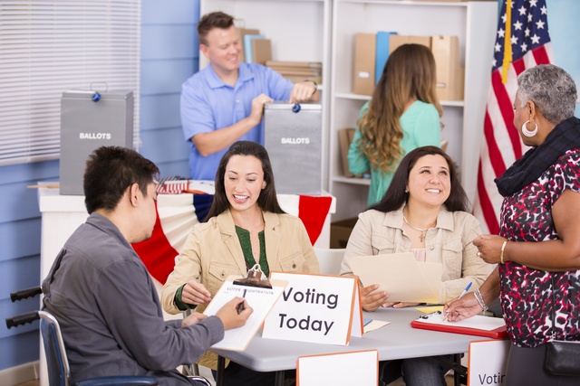 A man using a wheelchair signs in at to vote at his polling location