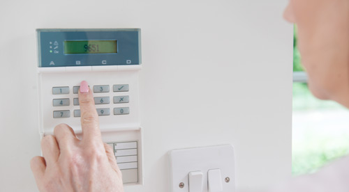 A white woman presses buttons on a security system